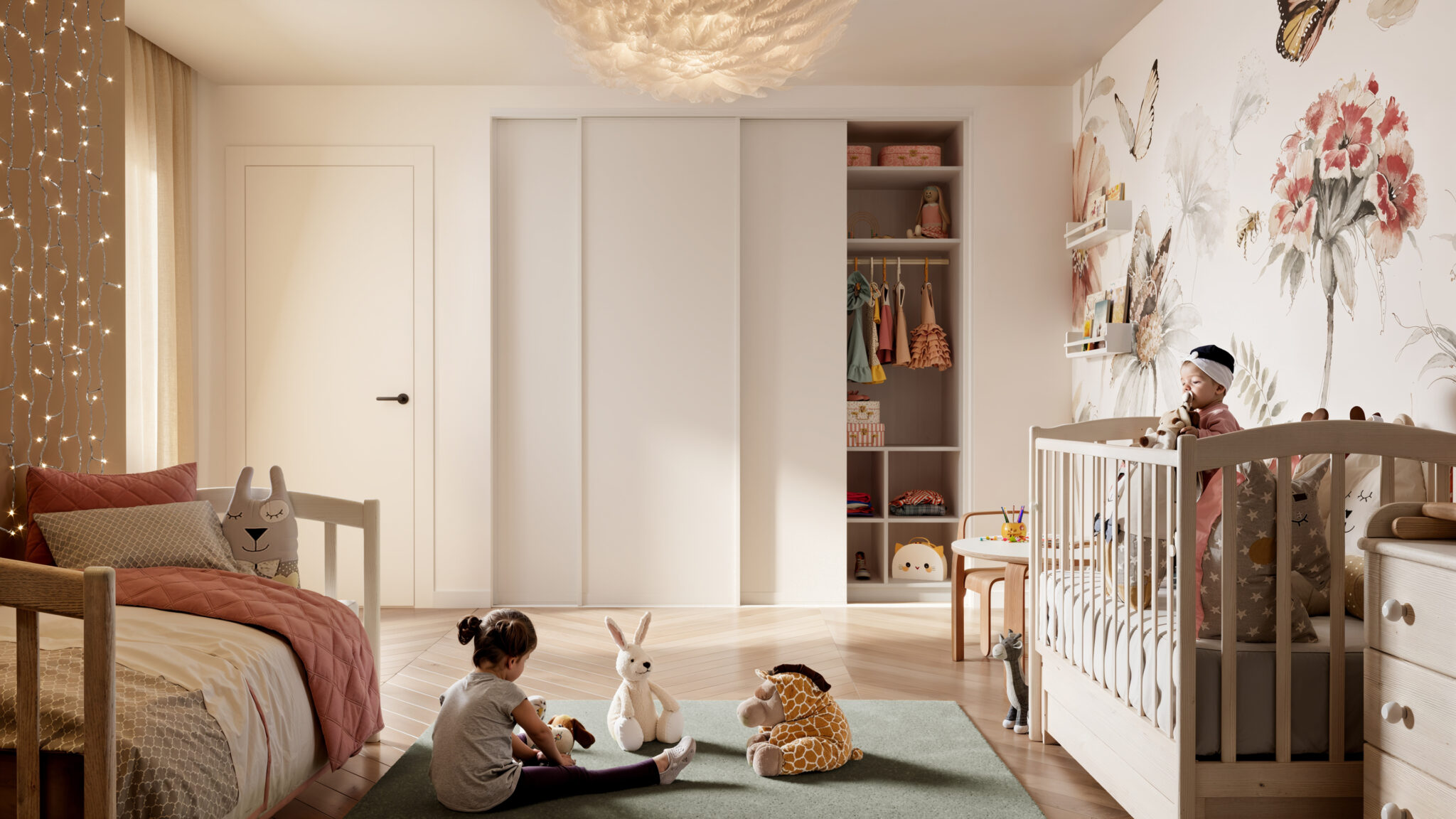 Deux enfants jouent dans une chambre décorée avec des peluches, un lit enfant et un papier peint floral.