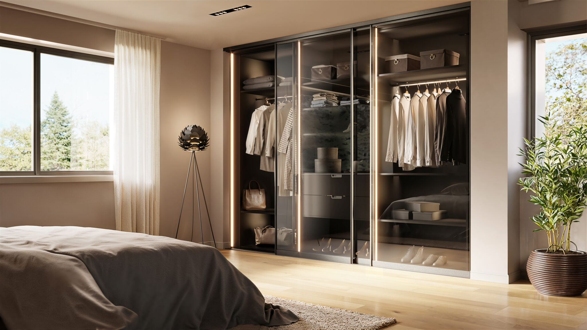 Armoire à portes vitrées éclairées, contenant des vêtements suspendus et des boîtes de rangement, près d'un lit et d'une plante verte.