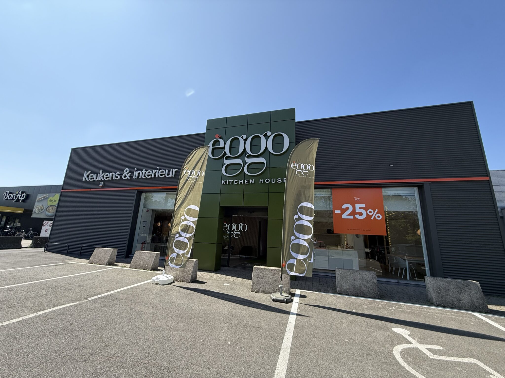 Façade d'un magasin èggo avec une enseigne verte, deux drapeaux promotionnels et une affiche rouge annonçant une réduction de 25%.