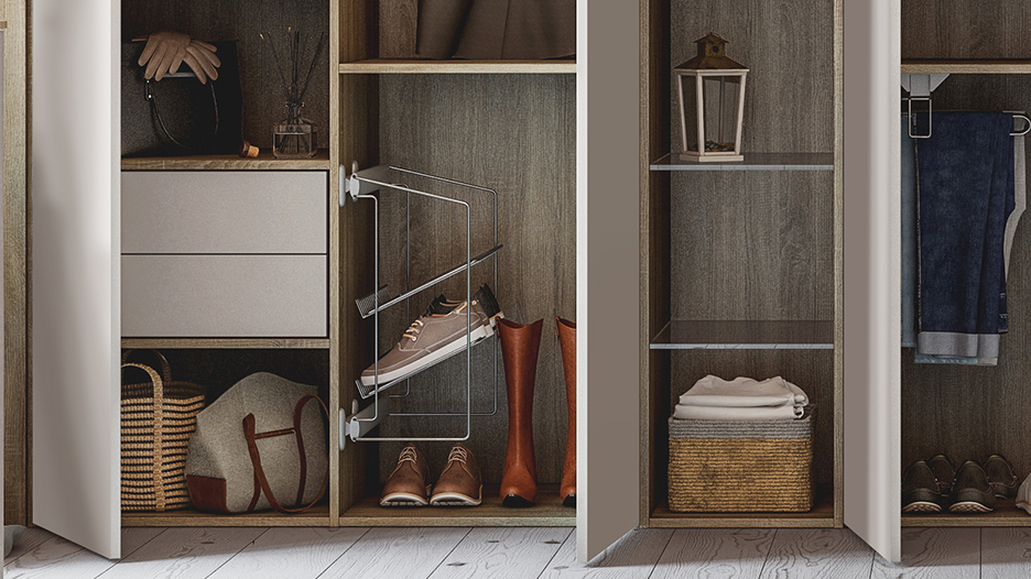 Chaussures et bottes rangées dans un meuble en bois avec étagères, tiroirs blancs, panier, lanterne, et vêtements suspendus.